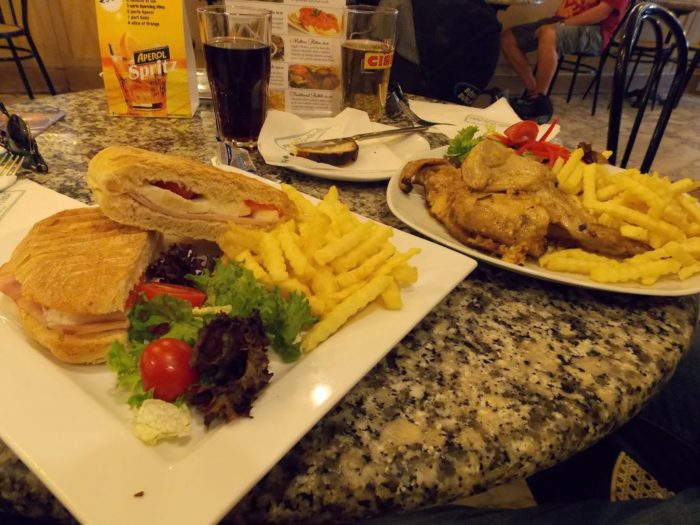 Caffe Cordina: à esquerda um sanduiche com o pão Ftira e a direita um coelho assado com fritas; uma Cisk ao fundo